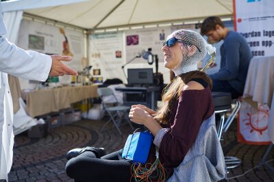 Person med netting med sensorer på hodet lærer om hjernen på Forskningstorget i Oslo